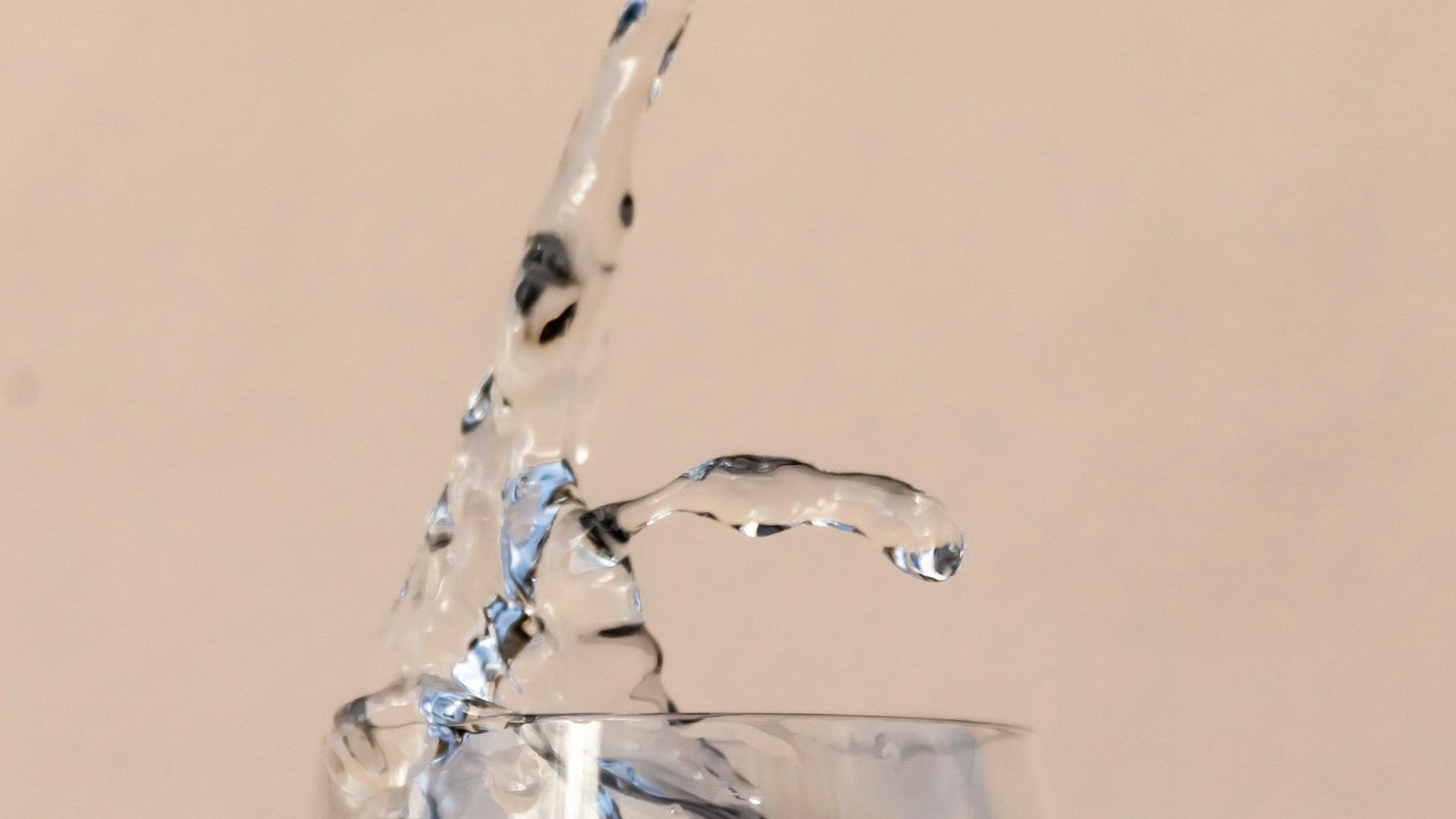 Clear water pouring into a drinking glass — the deliverable of Michigan's four statewide free-filter programs.